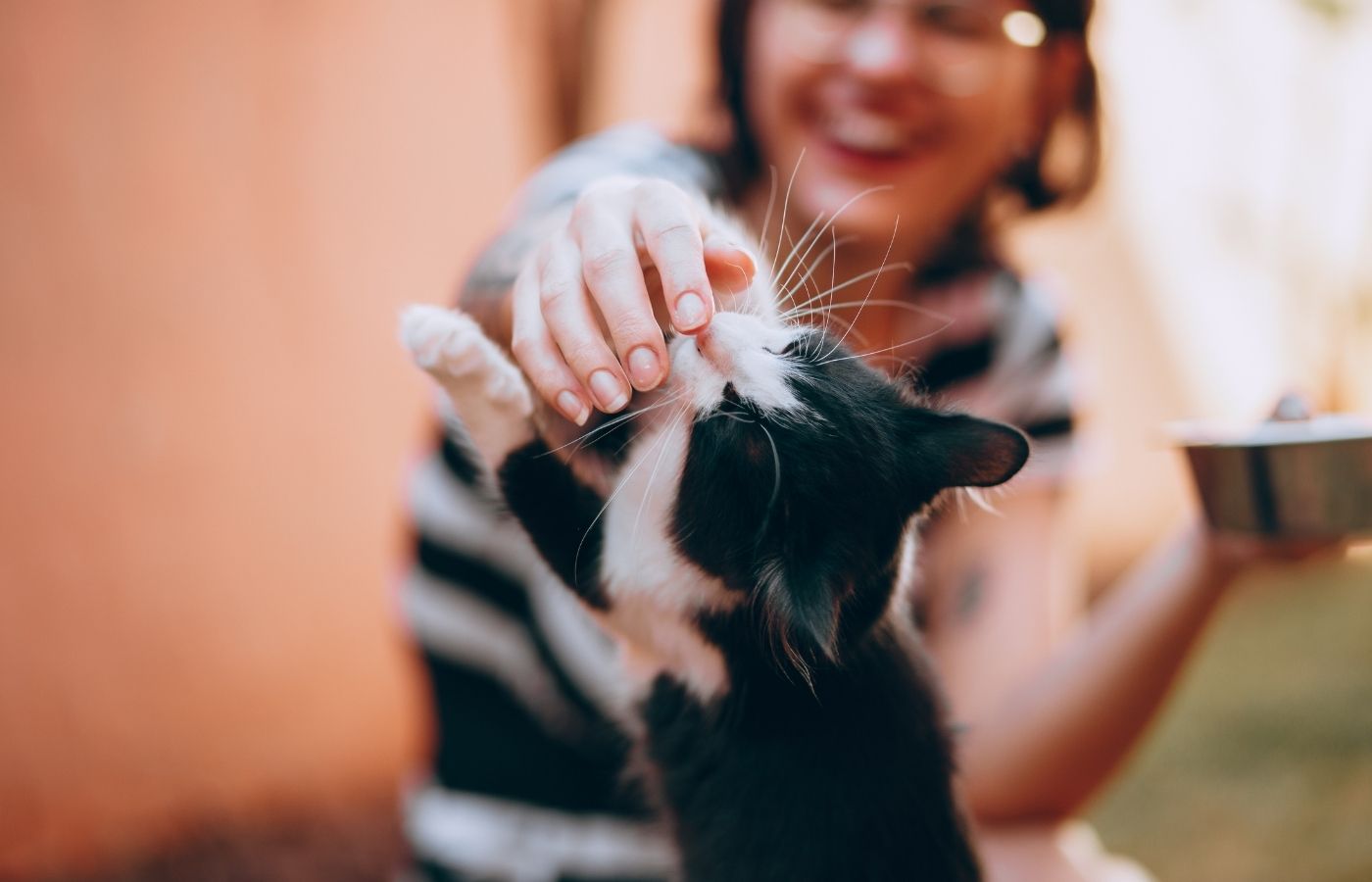 laughing woman playing with her black and white cat outdoors